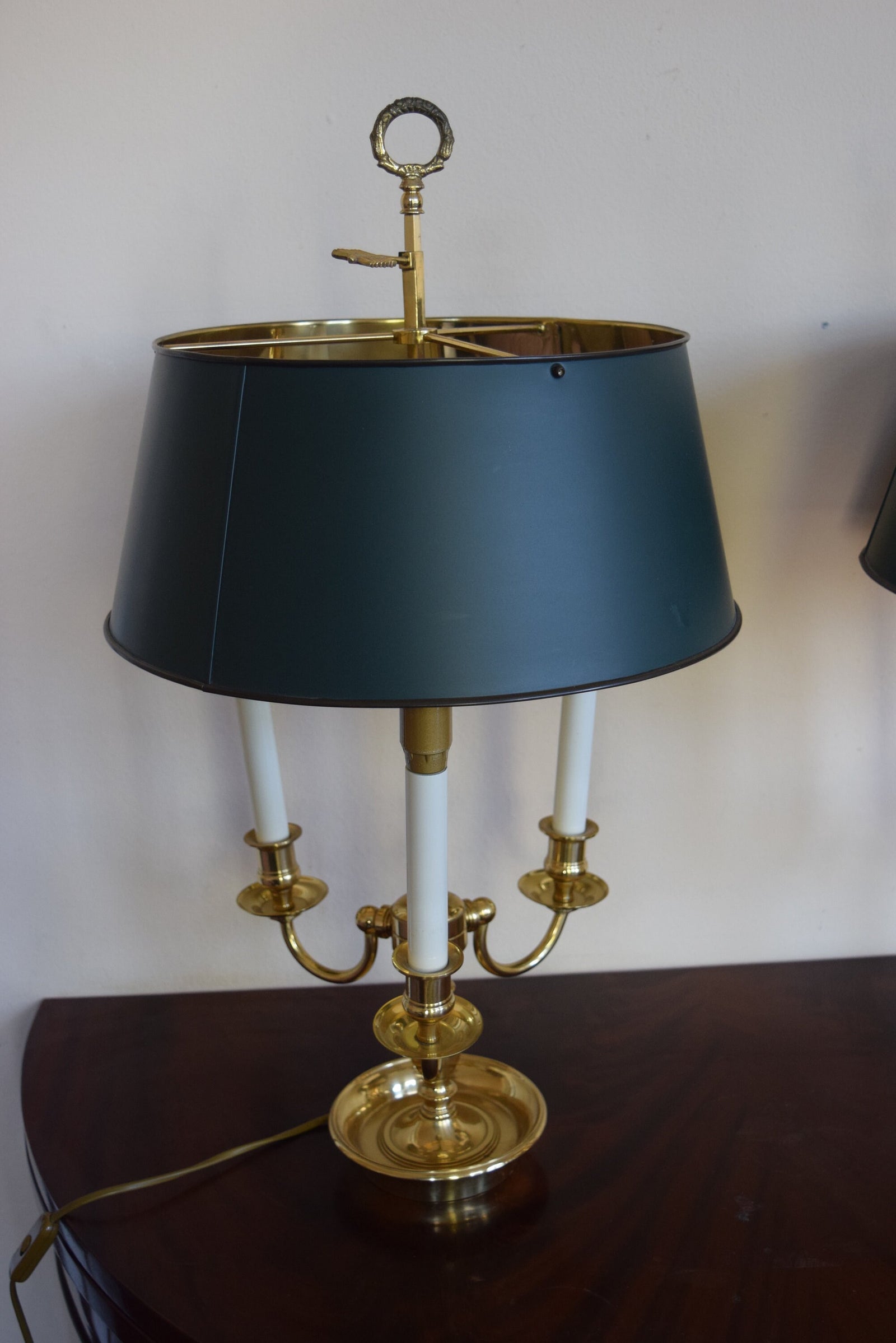 A pair of French Empire-style Bouillotte lamps with solid brass bases and deep green tole metal shades. Each lamp features three gracefully curved arms in a classic candelabra silhouette, exuding vintage sophistication. The adjustable shades allow for controlled lighting, perfect for desks, side tables, or elegant home decor. Ideal for lovers of antique lighting, French neoclassical design, and timeless statement pieces.