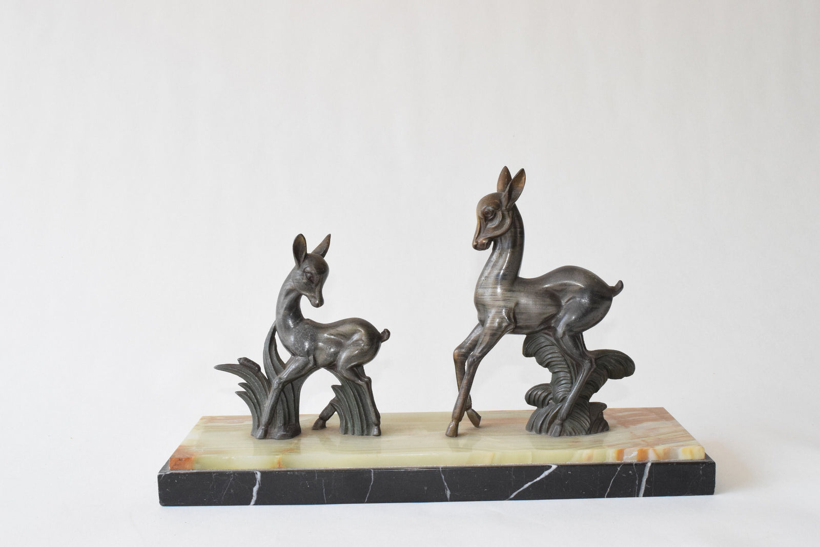 Art Deco deer sculpture featuring two elegant deer standing on a solid marble base. This vintage 1920s zalmac figurine captures the sleek, geometric aesthetic of the Art Deco era. A perfect collectible for art lovers, home decorators, or vintage enthusiasts, this sculpture enhances any space with its timeless elegance and sophisticated design. Ideal for display in homes, offices, or galleries.