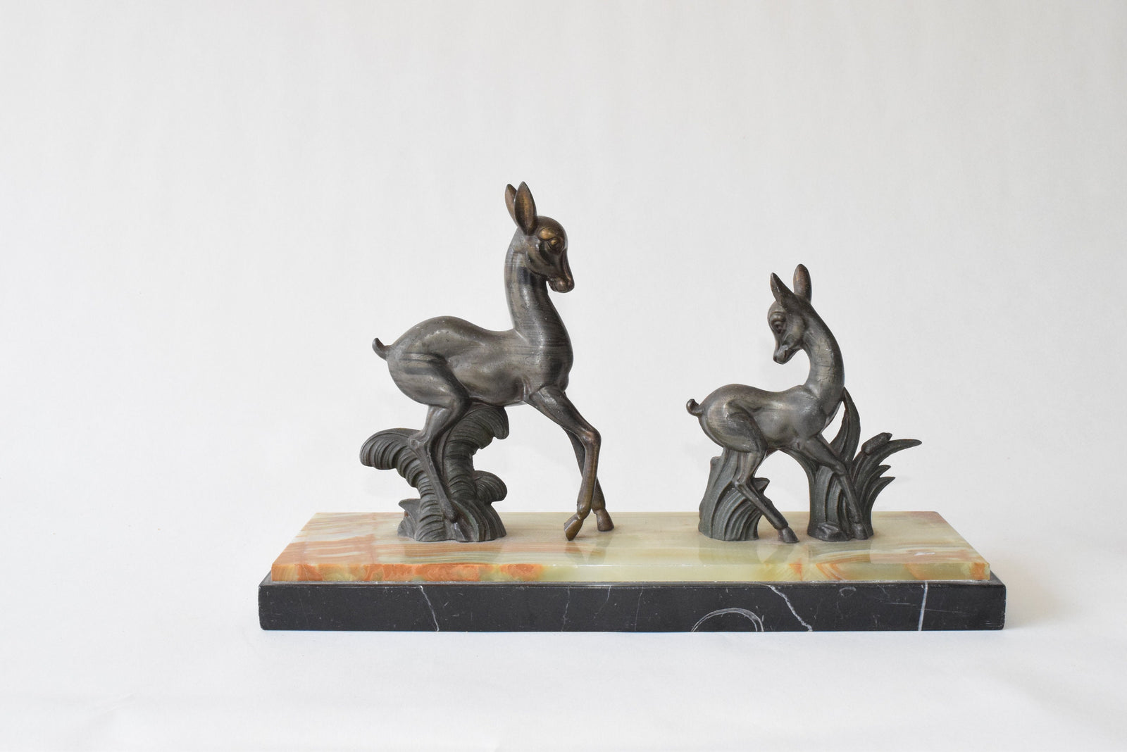 Art Deco deer sculpture featuring two elegant deer standing on a solid marble base. This vintage 1920s zalmac figurine captures the sleek, geometric aesthetic of the Art Deco era. A perfect collectible for art lovers, home decorators, or vintage enthusiasts, this sculpture enhances any space with its timeless elegance and sophisticated design. Ideal for display in homes, offices, or galleries.
