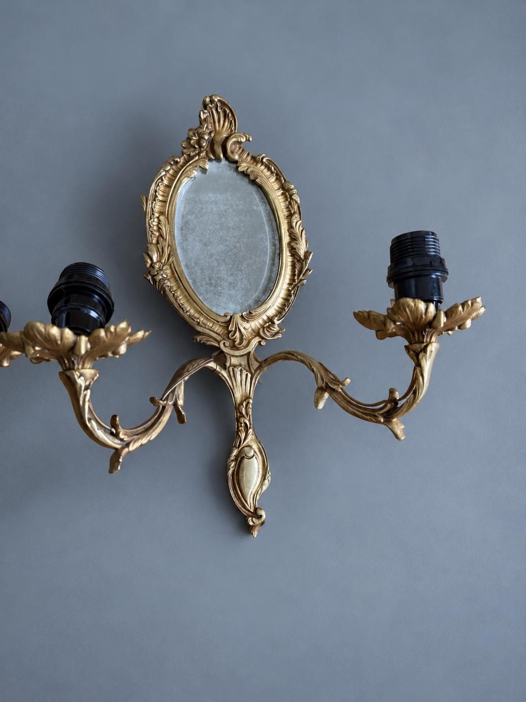 Vintage Pair of Rocaille Style Mirror Wall Sconces, Oval Bevelled Mirrors in Gilt Metal Frames, Leafy Two-Light Arms