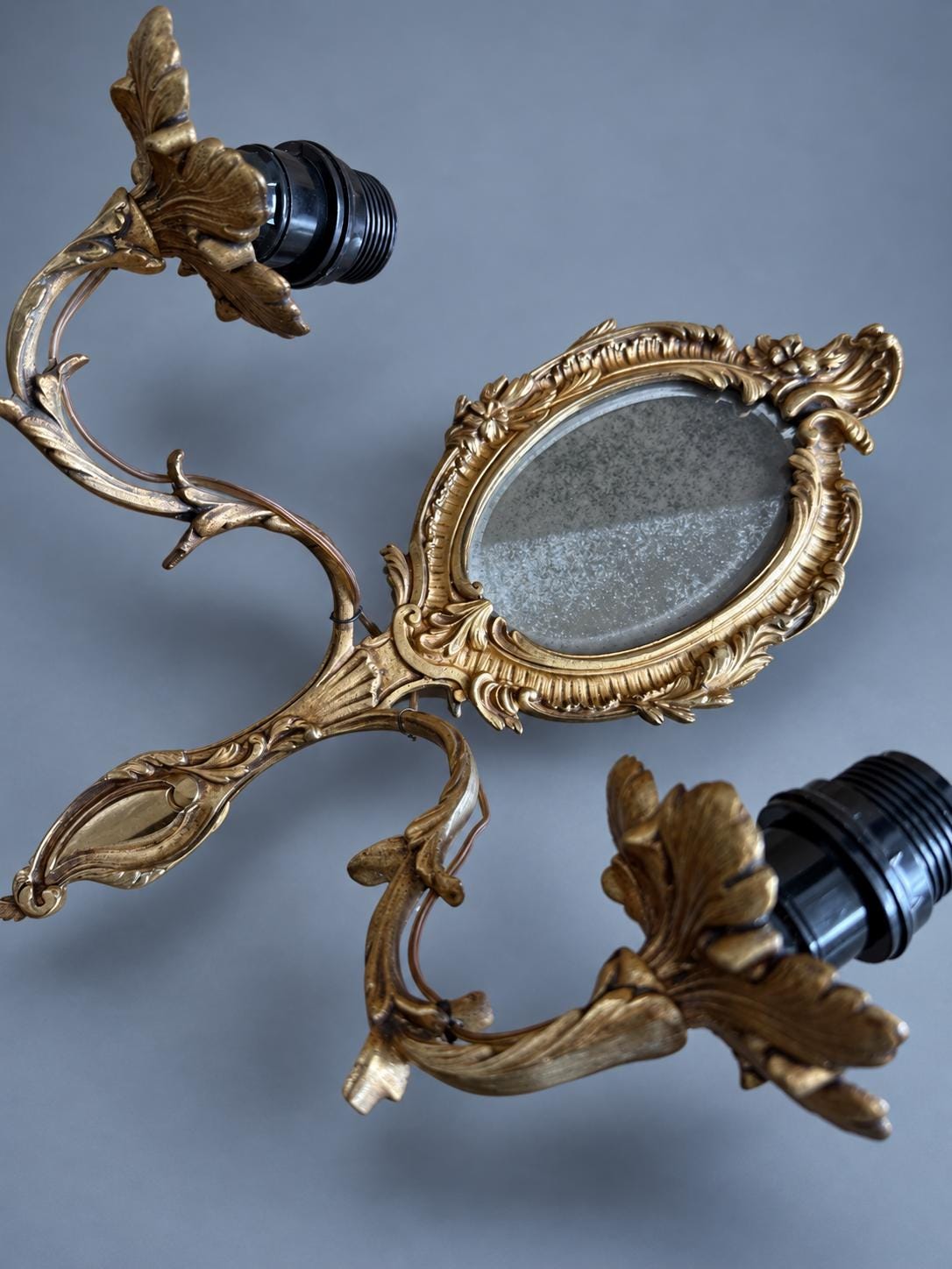 Vintage Pair of Rocaille Style Mirror Wall Sconces, Oval Bevelled Mirrors in Gilt Metal Frames, Leafy Two-Light Arms