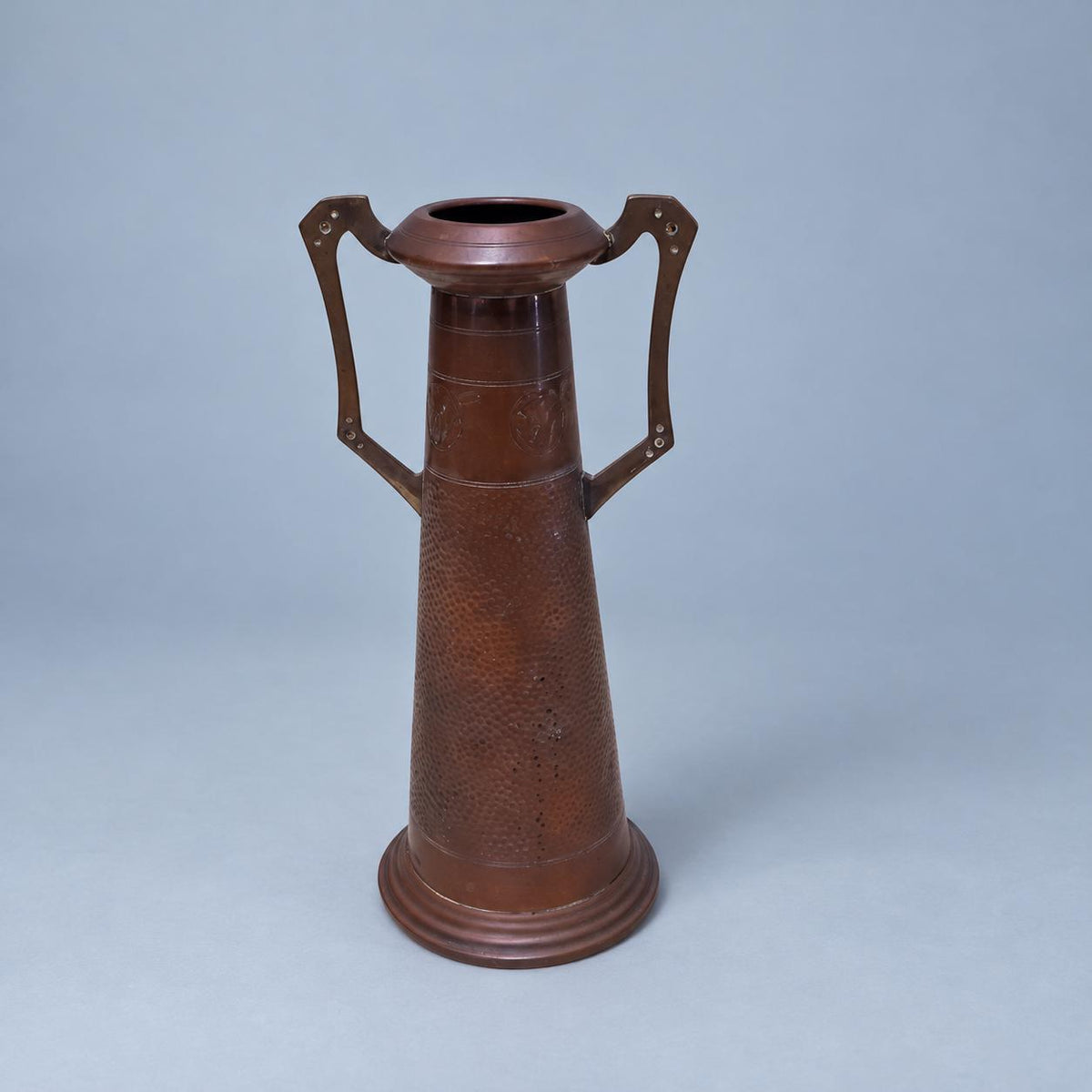 Vintage Art Nouveau Style Hammered Copper-Tone Vase with Angular Riveted Handles, Tall Tapering Form on Stepped Foot