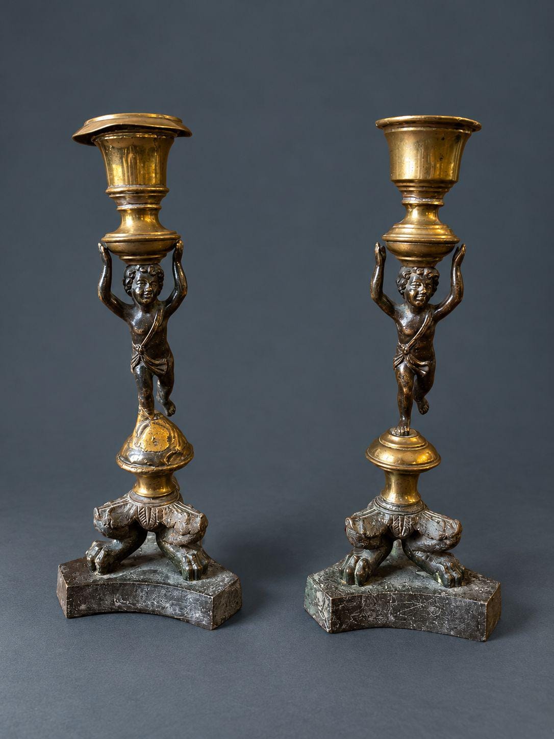 Pair of Antique Restauration Era Cherub Candlesticks, Bronze Putti Holding Brass Cups on Lion Paw Tripod Bases, 19th Century