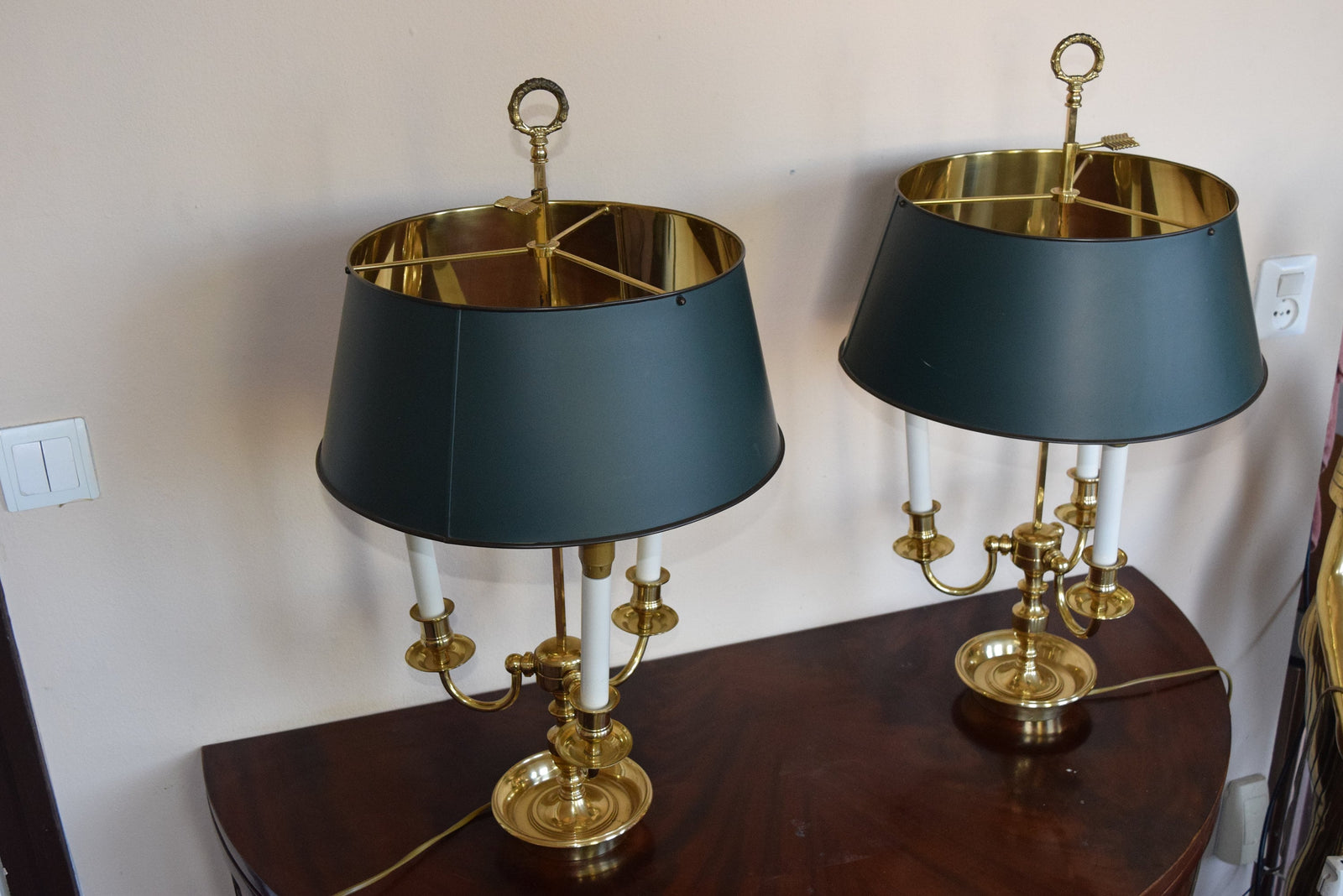 A pair of French Empire-style Bouillotte lamps with solid brass bases and deep green tole metal shades. Each lamp features three gracefully curved arms in a classic candelabra silhouette, exuding vintage sophistication. The adjustable shades allow for controlled lighting, perfect for desks, side tables, or elegant home decor. Ideal for lovers of antique lighting, French neoclassical design, and timeless statement pieces.