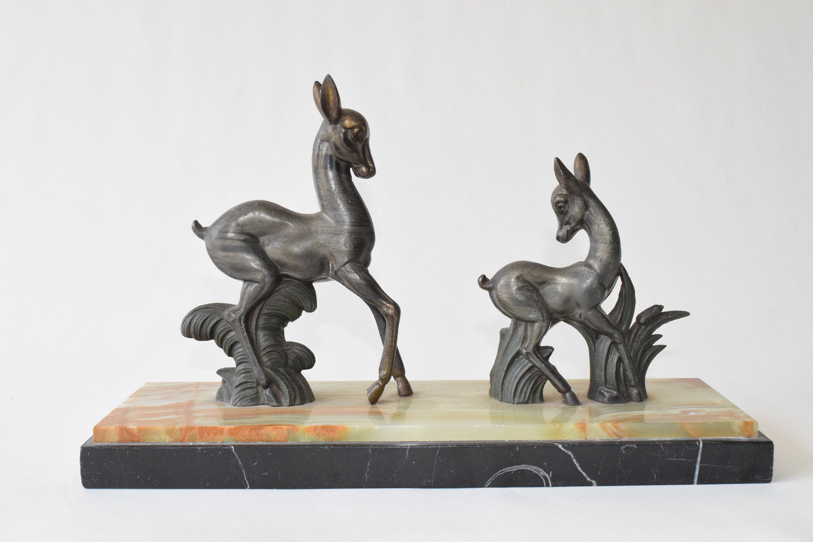 Art Deco deer sculpture featuring two elegant deer standing on a solid marble base. This vintage 1920s zalmac figurine captures the sleek, geometric aesthetic of the Art Deco era. A perfect collectible for art lovers, home decorators, or vintage enthusiasts, this sculpture enhances any space with its timeless elegance and sophisticated design. Ideal for display in homes, offices, or galleries.