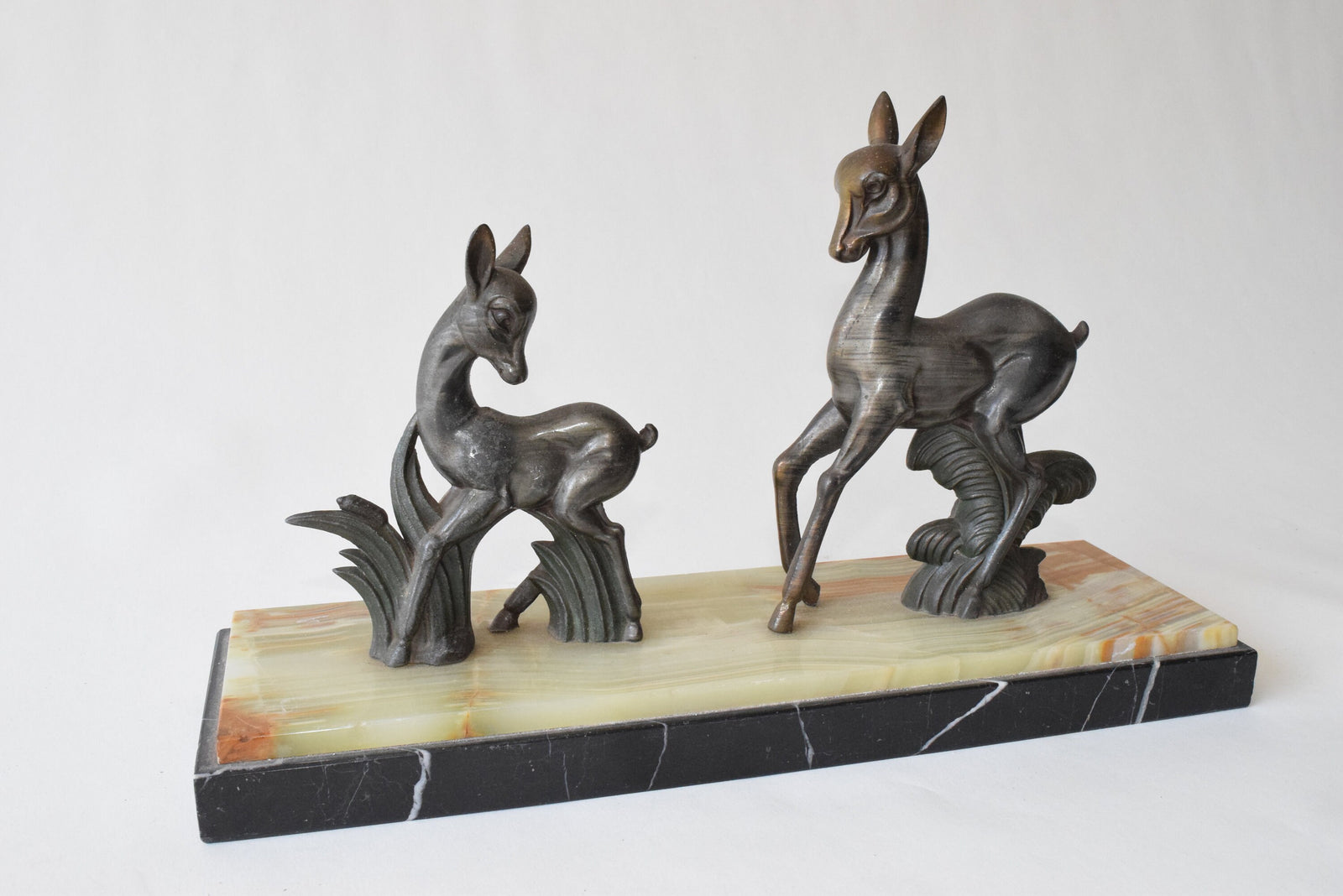 Art Deco deer sculpture featuring two elegant deer standing on a solid marble base. This vintage 1920s zalmac figurine captures the sleek, geometric aesthetic of the Art Deco era. A perfect collectible for art lovers, home decorators, or vintage enthusiasts, this sculpture enhances any space with its timeless elegance and sophisticated design. Ideal for display in homes, offices, or galleries.