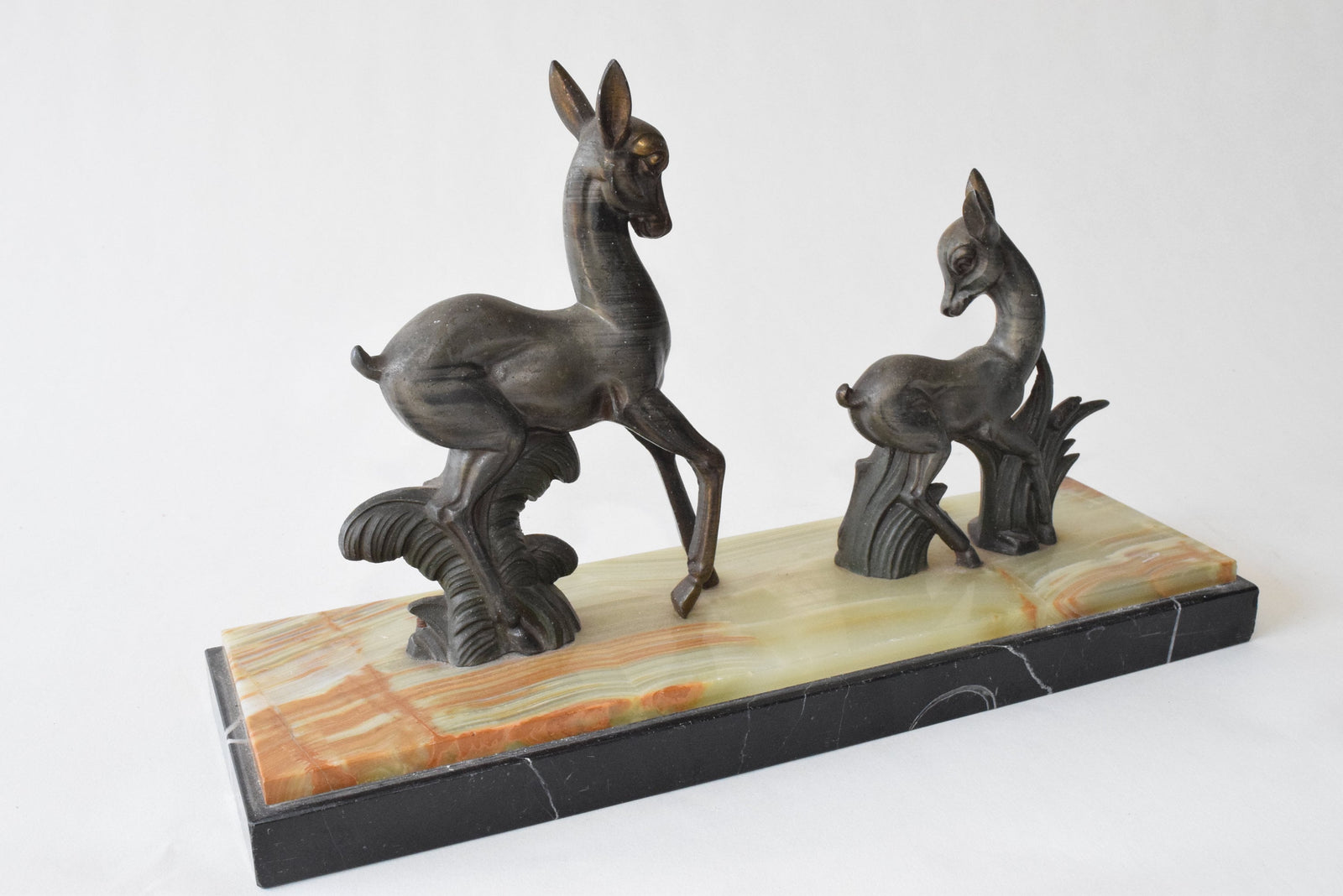 Art Deco deer sculpture featuring two elegant deer standing on a solid marble base. This vintage 1920s zalmac figurine captures the sleek, geometric aesthetic of the Art Deco era. A perfect collectible for art lovers, home decorators, or vintage enthusiasts, this sculpture enhances any space with its timeless elegance and sophisticated design. Ideal for display in homes, offices, or galleries.