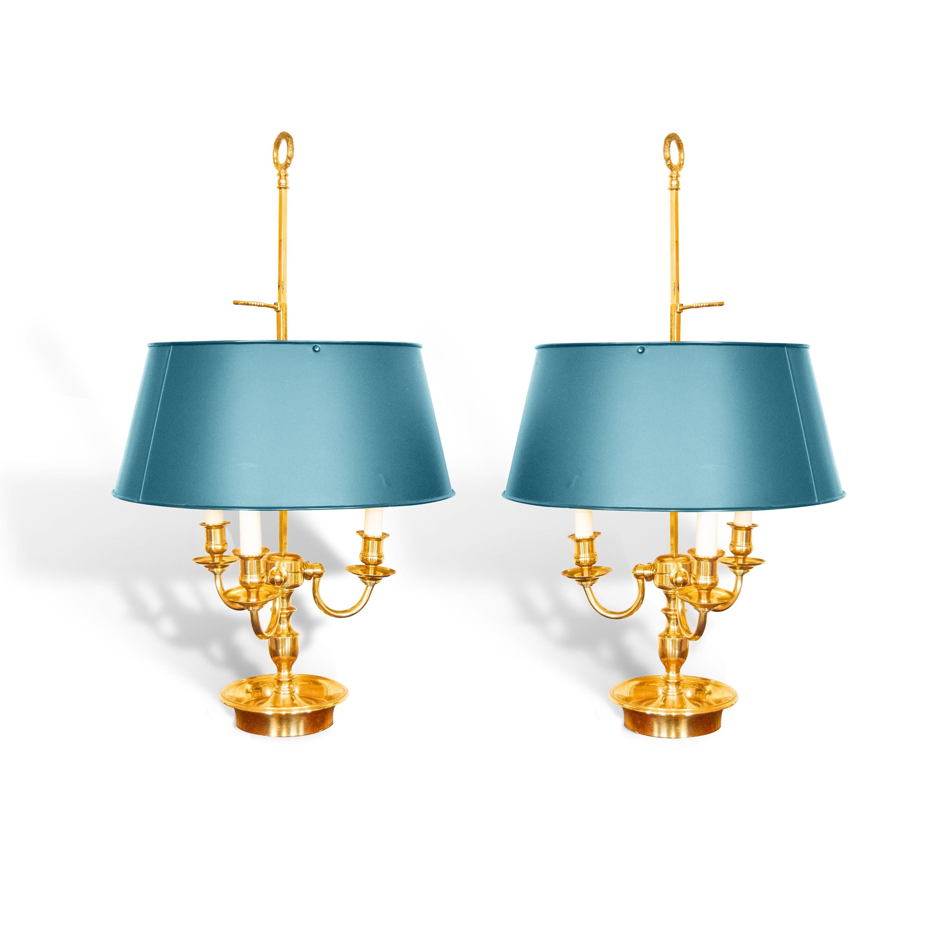 A pair of French Empire-style Bouillotte lamps with solid brass bases and deep green tole metal shades. Each lamp features three gracefully curved arms in a classic candelabra silhouette, exuding vintage sophistication. The adjustable shades allow for controlled lighting, perfect for desks, side tables, or elegant home decor. Ideal for lovers of antique lighting, French neoclassical design, and timeless statement pieces.