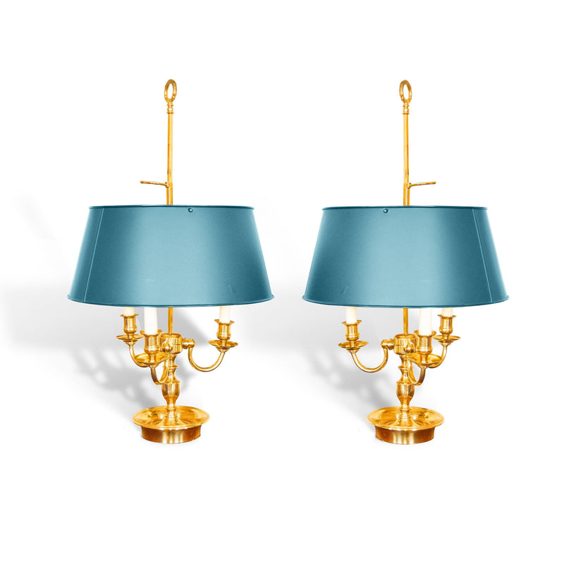 A pair of French Empire-style Bouillotte lamps with solid brass bases and deep green tole metal shades. Each lamp features three gracefully curved arms in a classic candelabra silhouette, exuding vintage sophistication. The adjustable shades allow for controlled lighting, perfect for desks, side tables, or elegant home decor. Ideal for lovers of antique lighting, French neoclassical design, and timeless statement pieces.