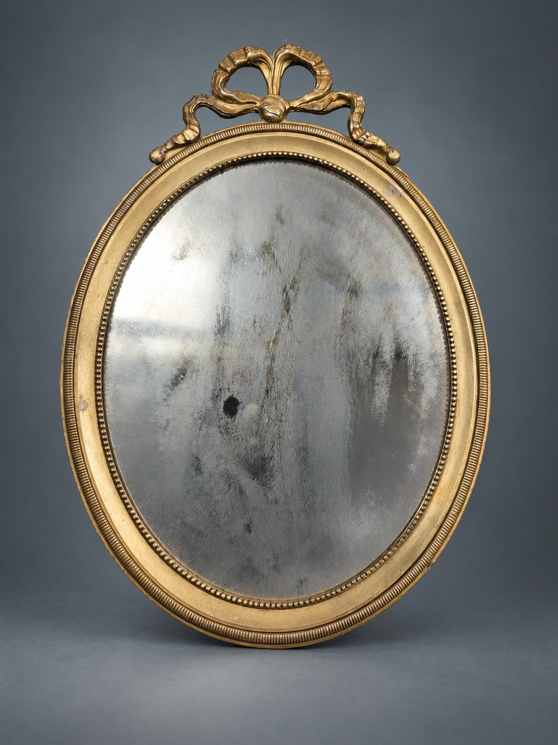 Small Oval Louis XVI Style Wall Mirror, Gilt Metal Frame with Ribbon-Bow Crest and Beaded Borders