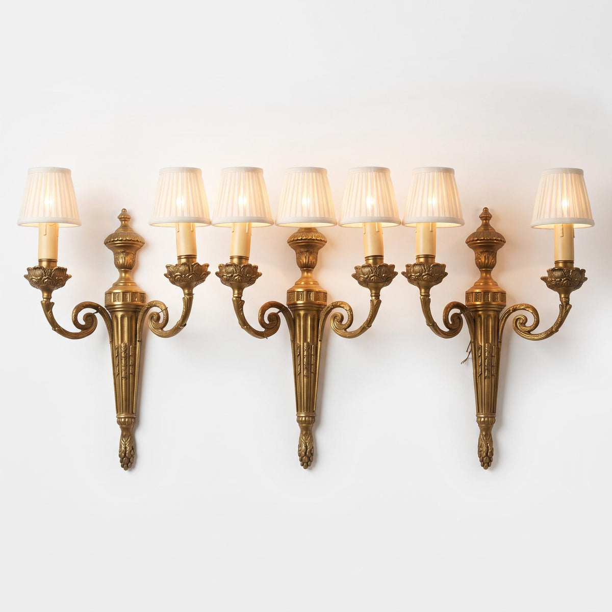 Set of Three Louis XVI Style Two-Arm Wall Sconces, Quiver Backplates with Ribbons, Leaf Cups and Pine Cone Drops