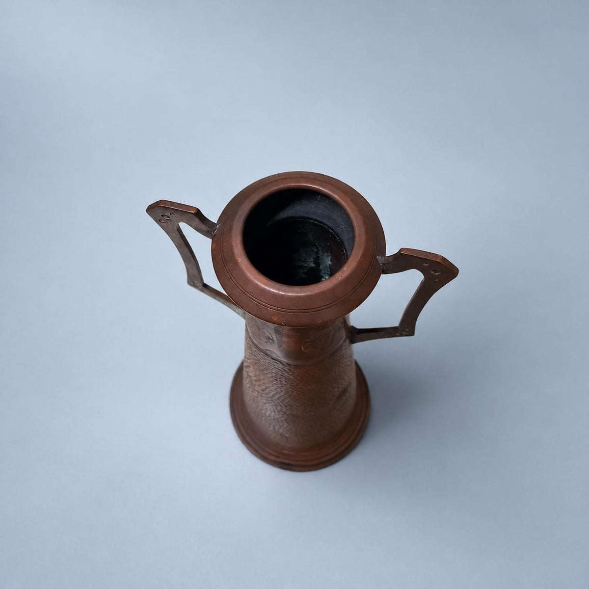 Vintage Art Nouveau Style Hammered Copper-Tone Vase with Angular Riveted Handles, Tall Tapering Form on Stepped Foot