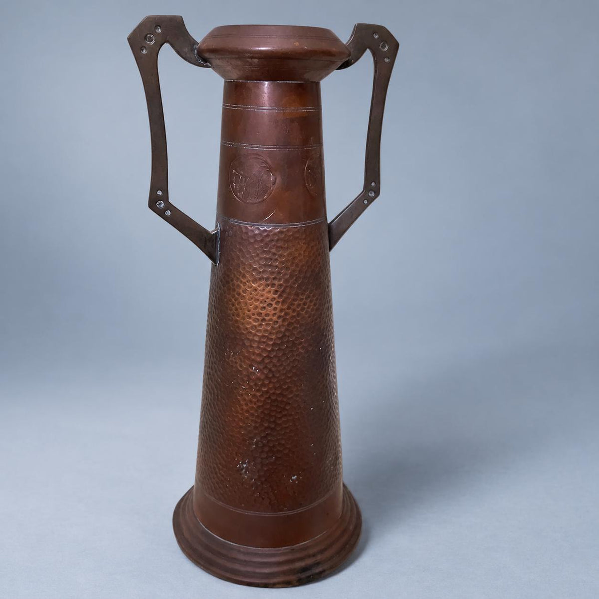 Vintage Art Nouveau Style Hammered Copper-Tone Vase with Angular Riveted Handles, Tall Tapering Form on Stepped Foot