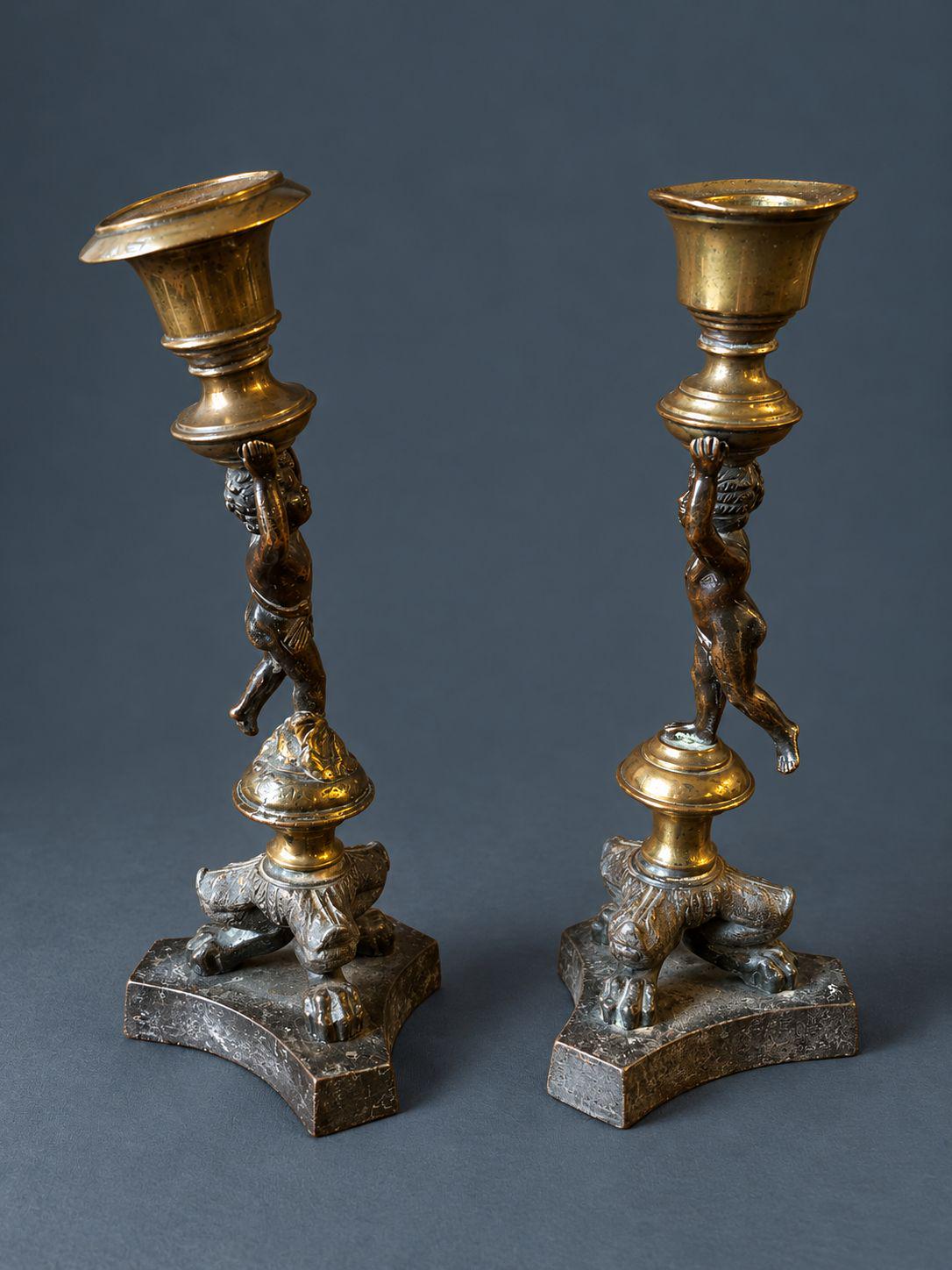 Pair of Antique Restauration Era Cherub Candlesticks, Bronze Putti Holding Brass Cups on Lion Paw Tripod Bases, 19th Century